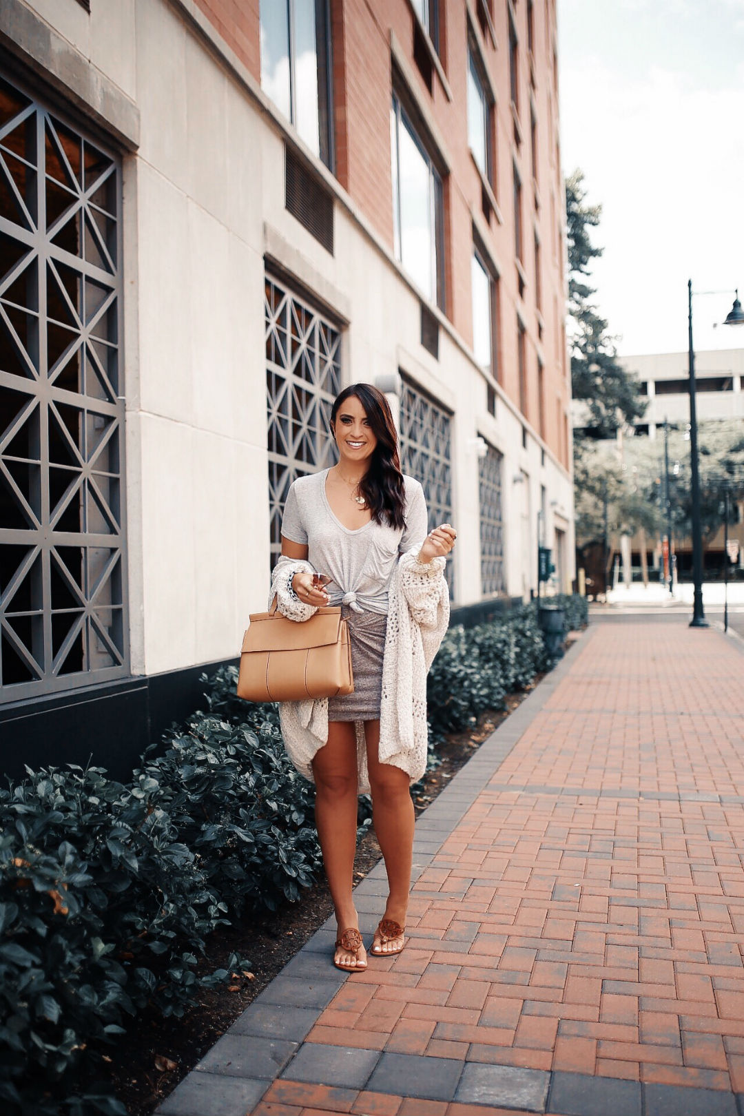 Blogger Sarah Lindner of The House of Sequins wearing Free People Saturday morning cardigan, BP twist front skirt and brown tory burch bag