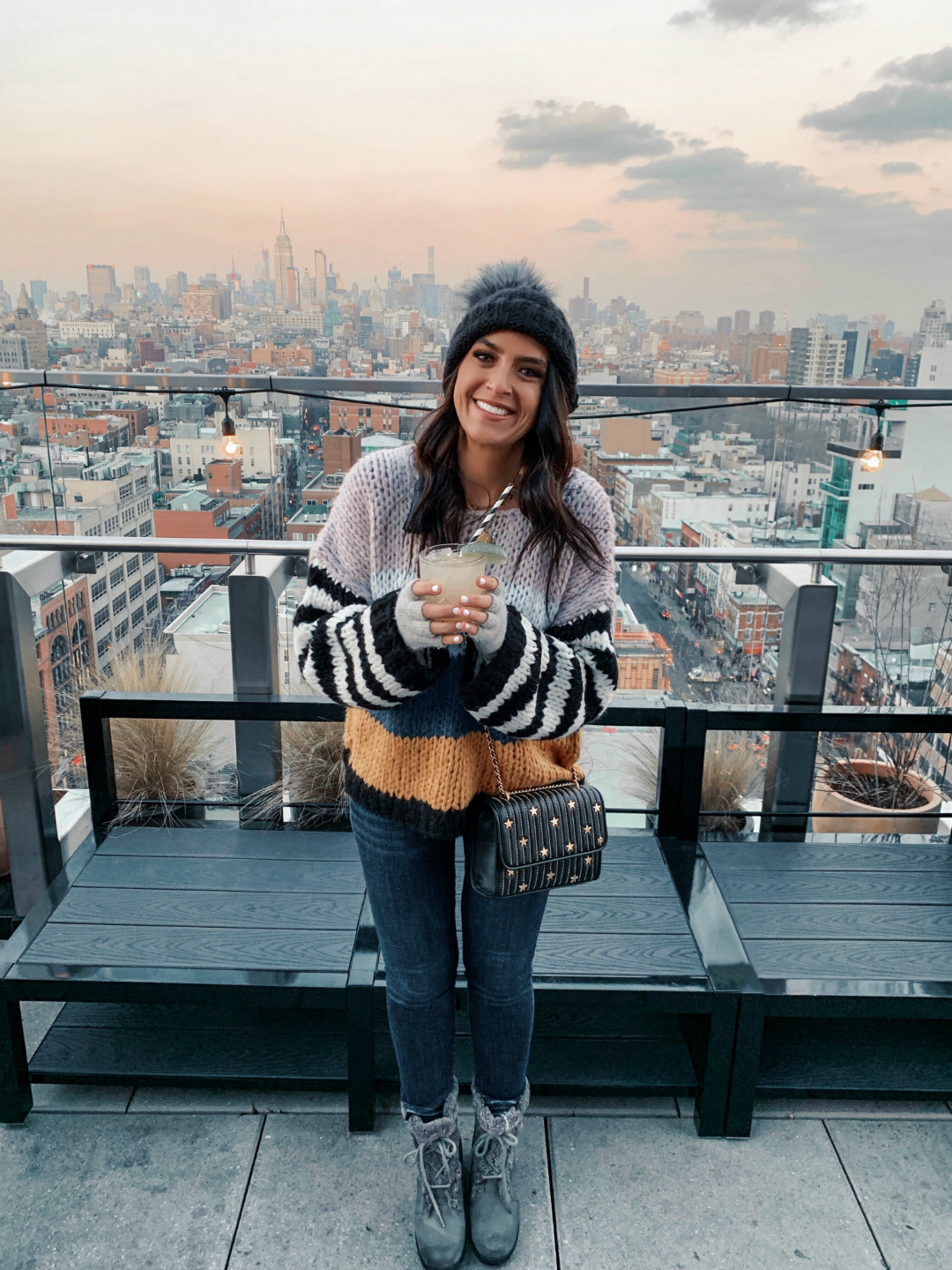 Blogger Sarah Lindner of The House of Sequins wearing Mixed Signals Mix Stripe Sweater from BlankNYC, Tory Burch Star-Stud bag, Kyi Kyi Beanie with genuine Fox Fur Pom and Sorel Joan of Arctic wedge boots. What to wear to NYC in the winter or Christmas time.