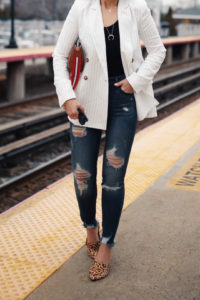blogger Sarah Lindner of The House of Sequins wearing Express Olivia Culpo Side Cut-Out Thong Body Suit, Express Olivia Culpo Striped Boyfriend Blazer, express Striped Strap Half Moon Crossbody Bag, and express High Waisted Ripped Denim Perfect Ankle Leggings