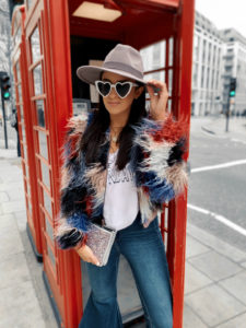 Blogger Sarah Lindner of The House of Sequins wearing Retro Brand Case of the Mondays tee, white heart sunglasses, Shaggy Faux Fur Jacket by Astr The Label, and free people Float On Flare Jeans