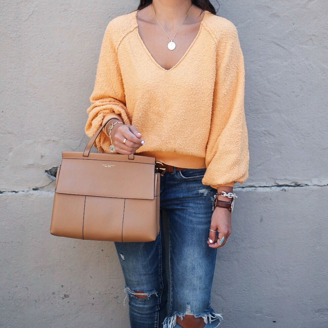 Blogger, Sarah Lindner of The House Of Sequins wearing a bright sweater with ripped jeans