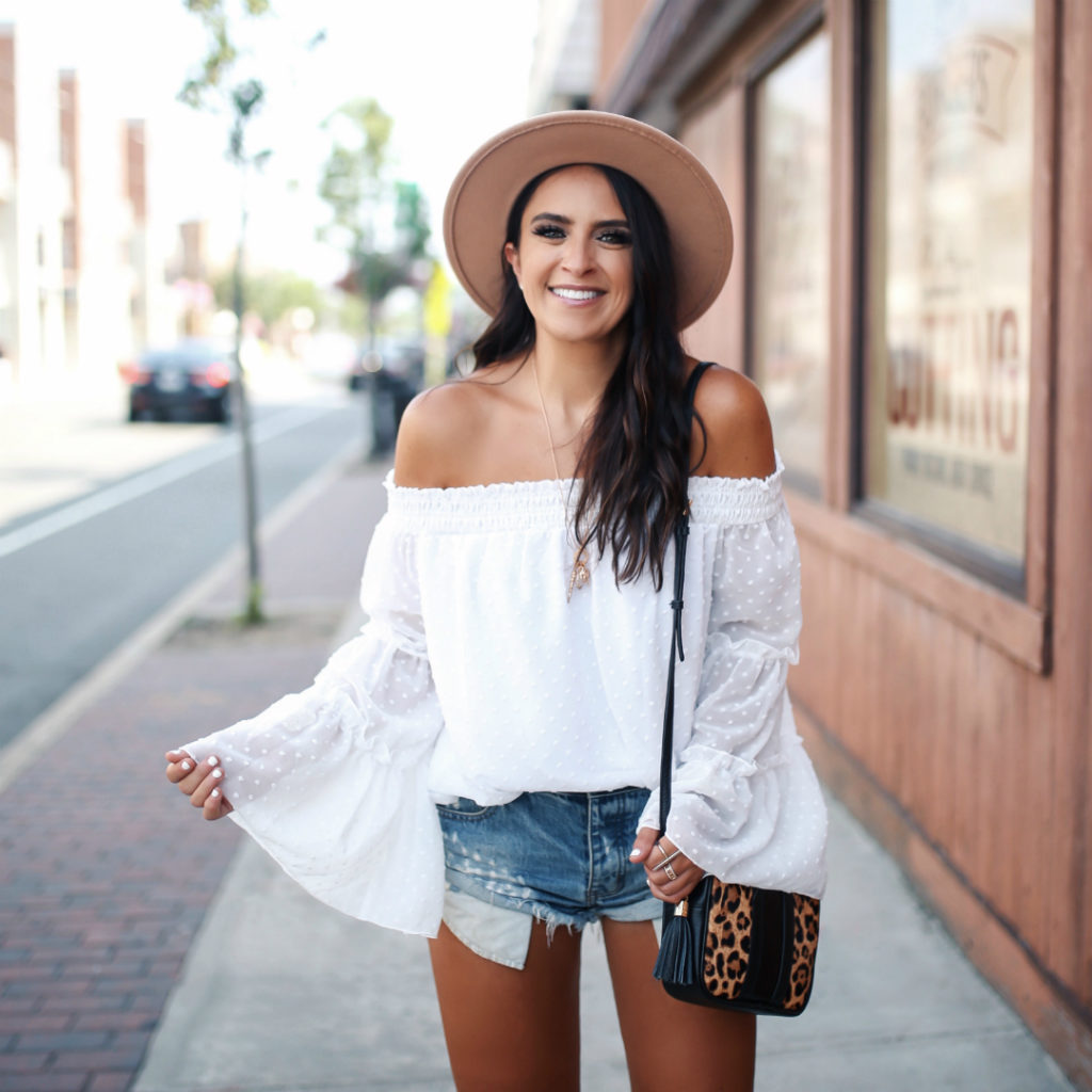 Blogger Sarah Lindner of The house of Sequins wearing a white off the shoulder top from amazon prime, one teaspoon bandit shorts, amazon brown wool hat, leopard gigi new york bag